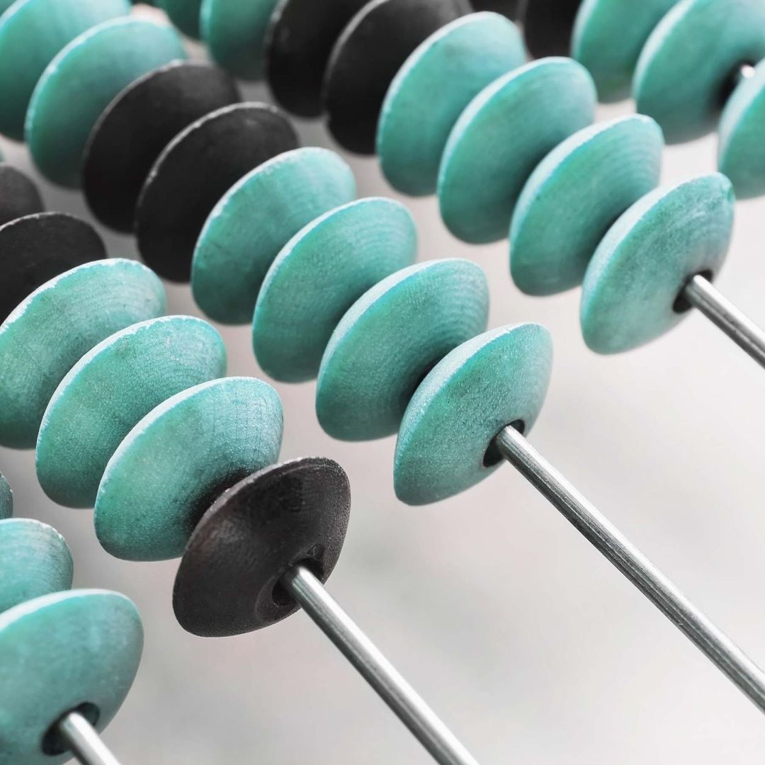 Abakus - Eine Reihe türkise und schwarzer Perlen auf einem Metallstab.